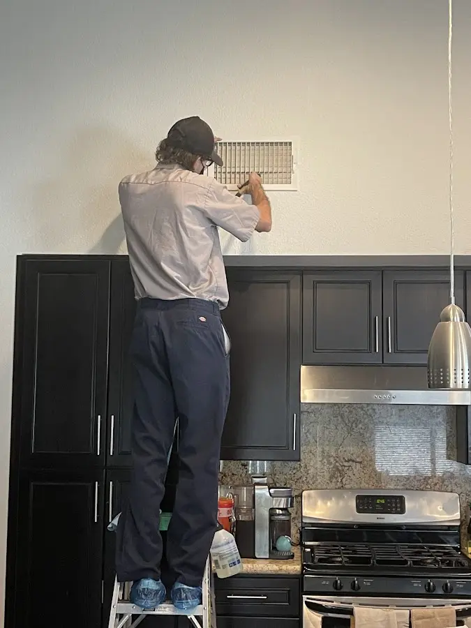 Technician inspecting an air vent during HVAC service in Modesto